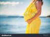 stock-photo-profile-of-pregnant-woman-with-long-hair-in-yellow-dress-on-the-beach-423009847.jpg