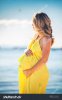 stock-photo-profile-view-of-pregnant-woman-with-long-hair-in-yellow-dress-on-the-beach-423009844.jpg