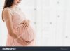 pregnant-woman-holding-belly-near-window-at-home-776622814.jpg