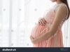 pregnant-woman-in-beautiful-pink-dress-standing-close-up-a-window-in-her-bedroom-761563120.jpg